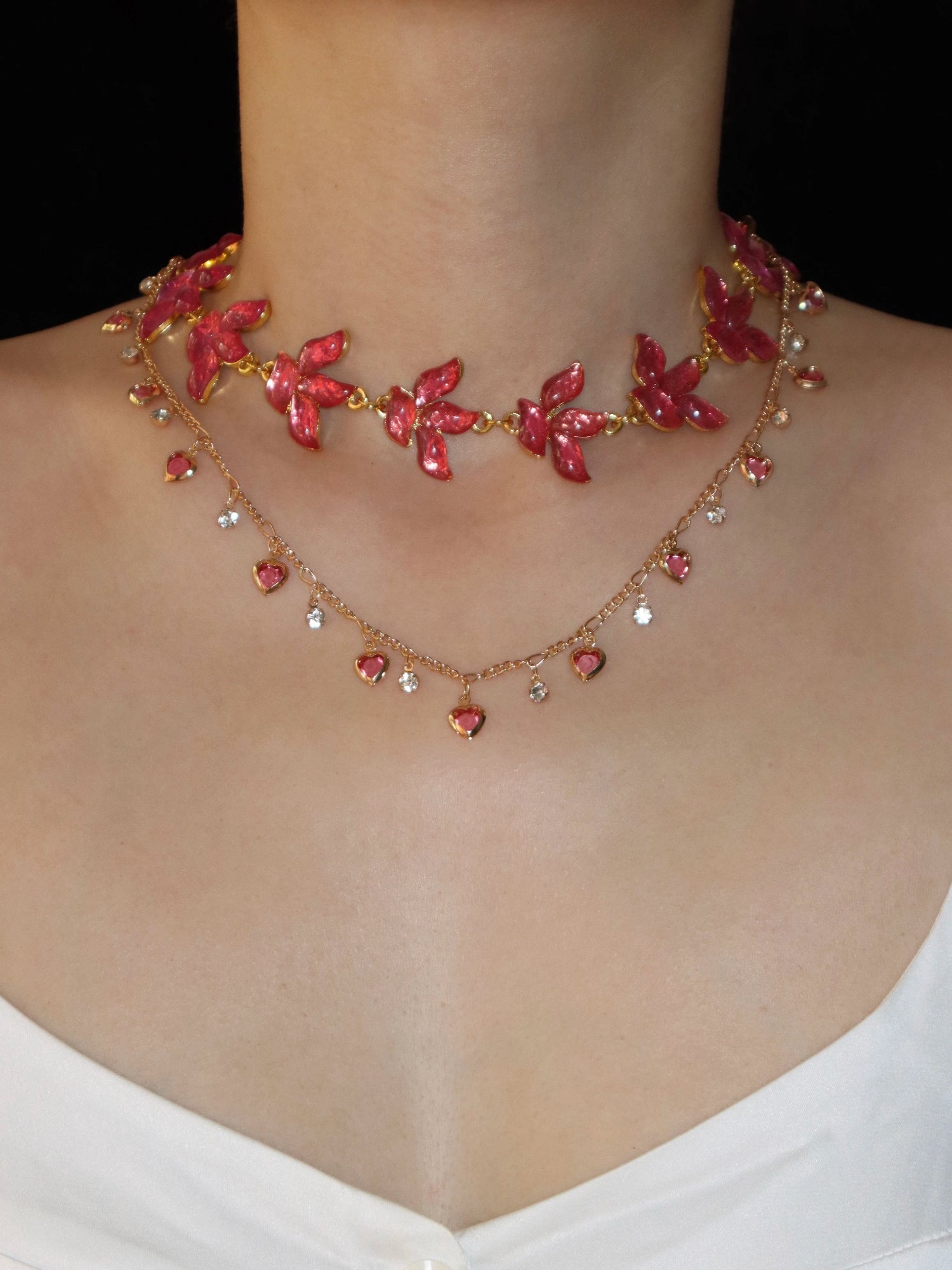 Necklace with red floral and heart-shaped beads on a person wearing a white top.